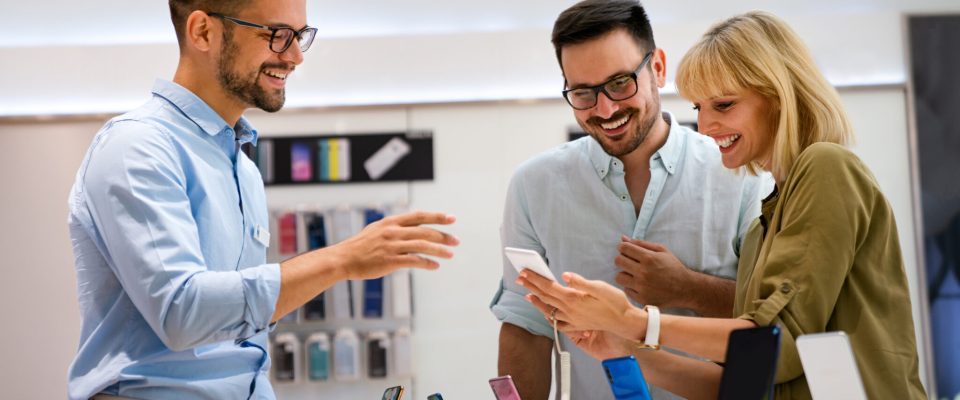 Portrait of salesman helping to people to buy a new digital device in tech shop