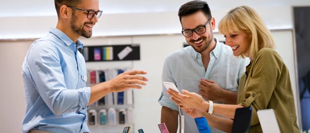 Portrait of salesman helping to people to buy a new digital device in tech shop