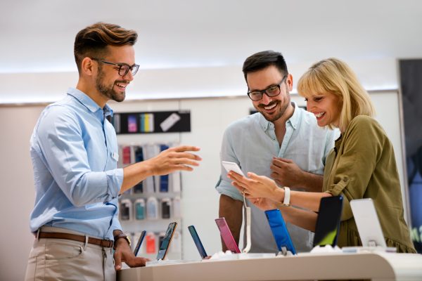 Portrait of salesman helping to people to buy a new digital device in tech shop